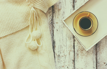 top view image of white cozy knitted sweater with to cup of coffee on a wooden tableの写真素材