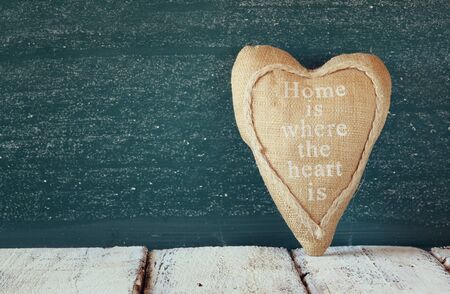 image of vintage fabric heart on wooden table in front of blackboard.の写真素材