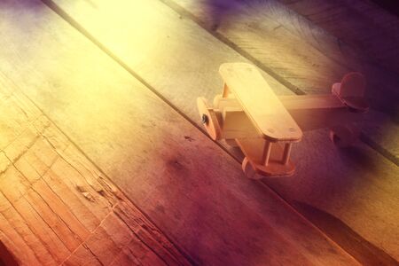 abstarct photo of wooden airplane toy over textured wooden background. retro style image. photographed without aditing software, using handmade filter.の写真素材