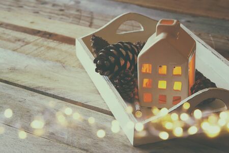 photo of decorative house and pine cones on wooden background. copy space.
