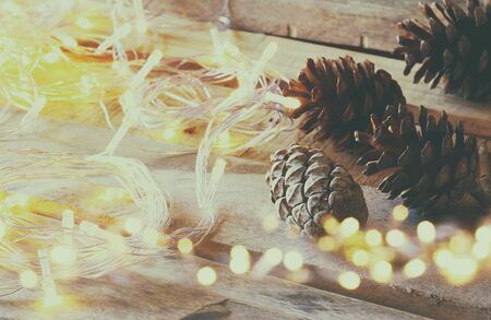 pine cones next to gold garland lights on wooden background. copy spaceの写真素材