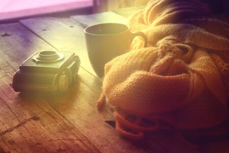 selective focus photo of pink cozy knitted scarf with to cup of coffee next to old photo camera on a...