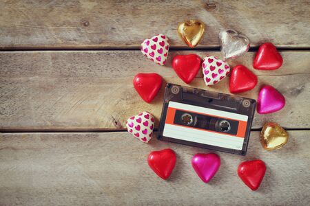 top view image of colorful heart shape chocolates and audio cassette on wooden table. valentine's day celebration conceptの写真素材