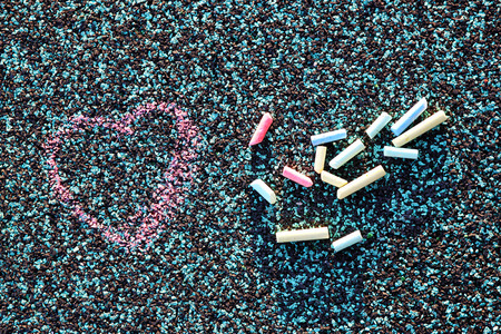 image of chalk hand drawing heart and collection of many colorful chalks. filtered image. selective focusの写真素材