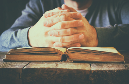 low key image of person sitting next to prayer bookの写真素材