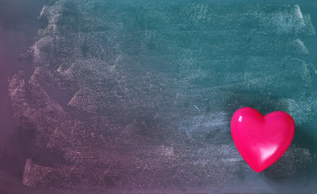 top view image of pink plastic heart on blackboard background. valentine's day celebration concept. filtered and toned photoの写真素材