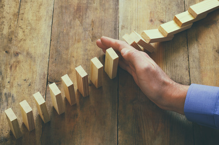 a male hand stoping the domino effect. retro style image executive and risk control conceptの写真素材