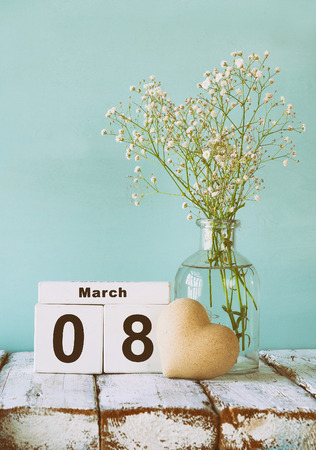 wooden March 8 calendar, next to heart and white flowers on old rustic table. selective focusの写真素材