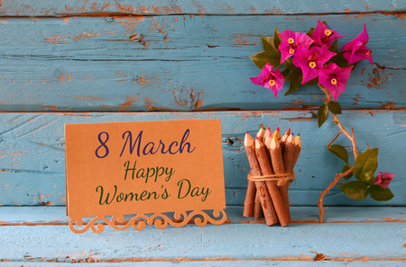 vintage card with phrase: 8 march happy womens day on wooden texture table next to purple bougainvillea flower.の写真素材