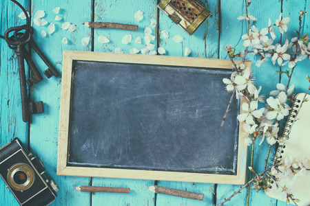 top view image of spring white cherry blossoms tree, blackboard, old camera on blue wooden tableの写真素材