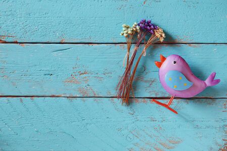 top view image of dried colorful flowers next to bird toy on old blue wooden backgroundの写真素材
