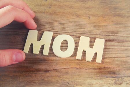 word MOM made with block wooden letters on wooden background. vintage filtered and tonedの写真素材