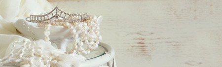 website banner background of white pearls necklace and diamond tiara on vintage table. toned image. selective focusの写真素材
