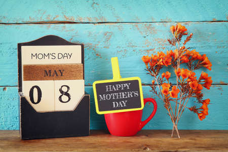 flowers next to blackboard, on wooden table. happy mother's day conceptの写真素材