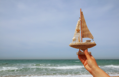woman's hands holding a boat in front of sea horizonの写真素材