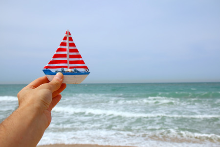 man's hands holding a boat in front of sea horizonの写真素材