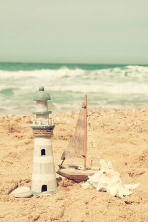 lighthouse, sailboat on sea sand and ocean horizonの写真素材