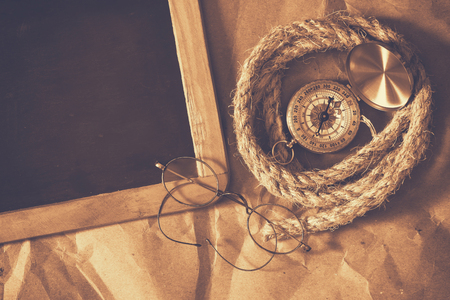 top view of compass, rope, old glasses and blank blackboard. explorer and adventure concept. sepia vintage filteredの写真素材