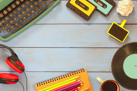 top view image of eightees style objects over wooden table.  typewriter cassettes,  record and...
