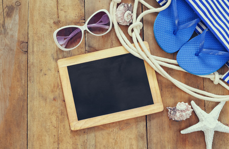 top view image of beach accessories and blank blackboard on wooden deck. copy space.