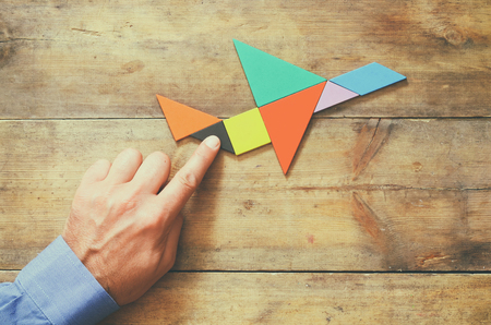 man's hand pointing at plane made from square tangram puzzleの写真素材