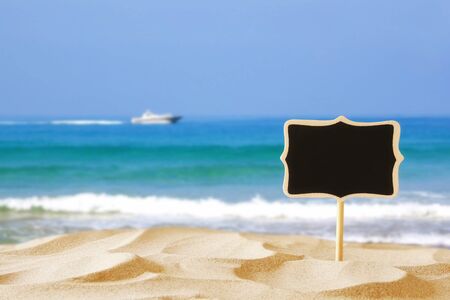Image of tropical sandy beach and blank wooden chalkboard sign. Summer conceptの写真素材