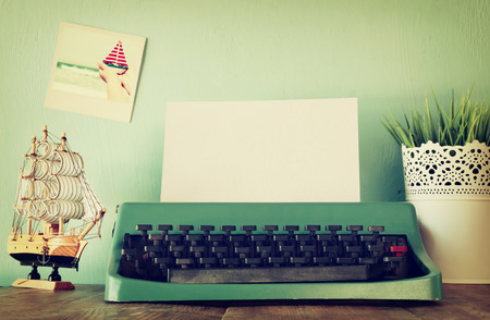 Photo of vintage typewriter with blank page on wooden tableの写真素材