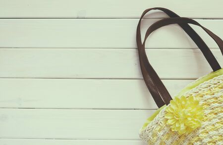 Top view of woman vacation beach bag on white wooden background. Retro filtered and toned