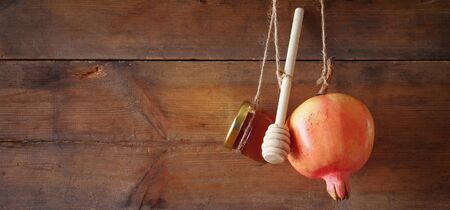 Rosh hashanah (jewish New Year holiday) concept - honey and pomegranate over wooden background.の写真素材