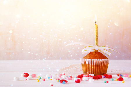 Birthday concept with cupcake and candle on wooden table. Glitter overlayの写真素材