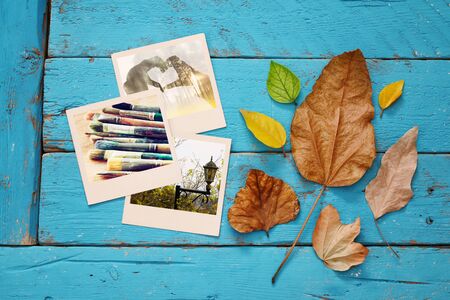 Autumn background with dry leaves and old photo frames on blue wooden table