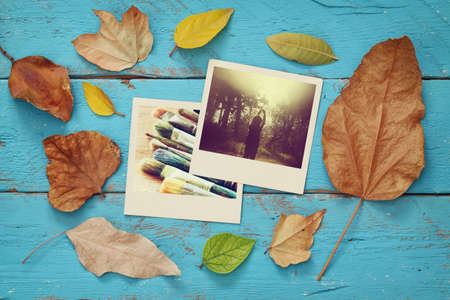 Autumn background with dry leaves and old photo frames on blue wooden tableの写真素材
