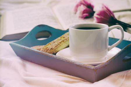 Romantic breakfast in the bed: cookies, hot coffee, flowers and open book. vintage style filtered and tonedの写真素材