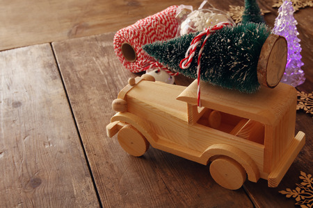Wooden car carrying a christmas tree on wooden floor.の写真素材