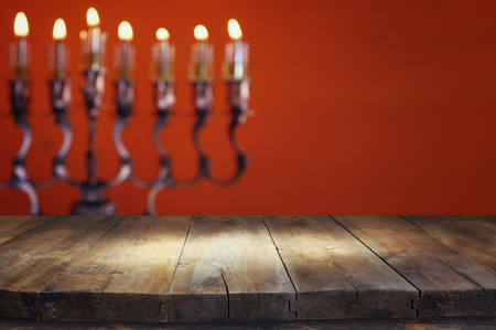 Empty wooden table in front of jewish holiday Hanukkah background with menorah (traditional candelabra) and burning candlesの写真素材