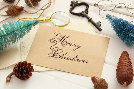 Top view of pine cones, greeting card, christmas tree and vintage objects on white wooden backgroundの写真素材