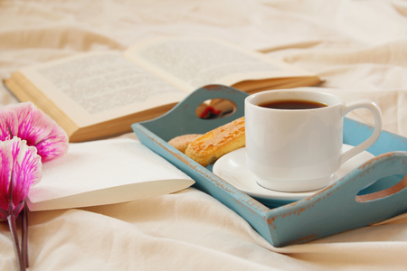 Romantic breakfast in the bed: cookies, hot coffee, flowers and blank note for adding textの写真素材