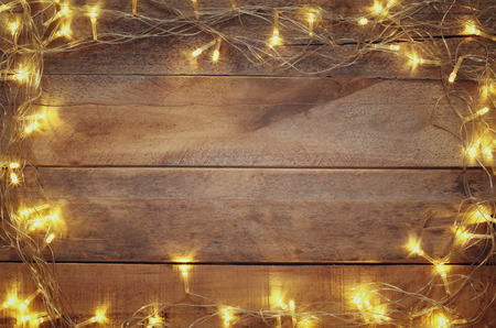 image of Christmas warm gold garland lights on wooden rustic background. filtered image. selective...