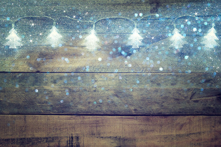 image of Christmas tree garland lights on wooden rustic background. glitter overlay. selective focus.の写真素材