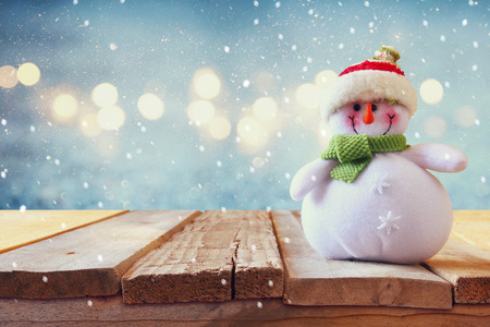 Cute snowman on wooden table. Snow overlay.の写真素材