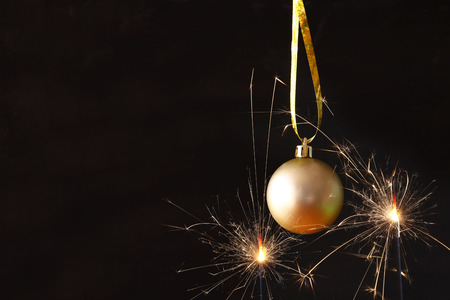 Image of christmas festive tree gold ball decoration in front of black background and fireworks