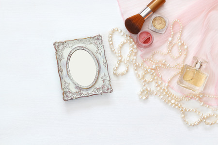 Top view image of vintage woman toilet accessory next to blank photo frame on the tableの写真素材