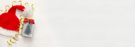 Image of cute knitted santa hat and mason jar with christmas tree. Website banner format