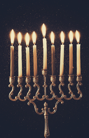 Low key Image of jewish holiday Hanukkah background with menorah (traditional candelabra) and burning candles. Sepia style photoの写真素材