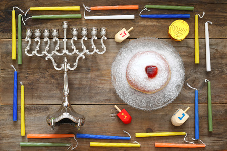 Image of jewish holiday Hanukkah with menorah (traditional Candelabra), donut and wooden dreidel (spinning top)の写真素材