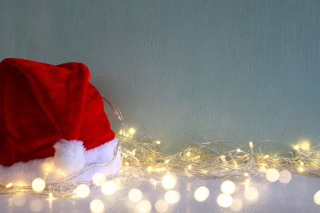 Low key Image of christmas garland warm lights next to santa hat