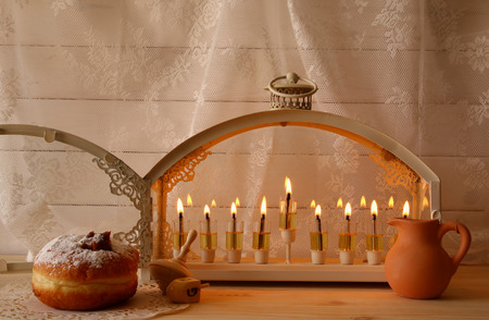 Low key image of jewish holiday Hanukkah with menorah (traditional Candelabra), donuts and wooden dreidel (spinning top). Selective focusの写真素材
