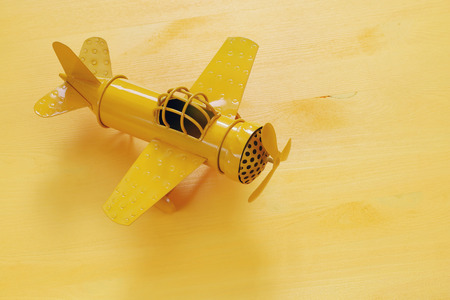 image of retro yellow metal toy airplane over wooden table.の写真素材