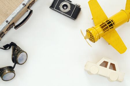 Top view of vintage yellow toy plane, old photo camera, pilot glasses and suitcaseの写真素材