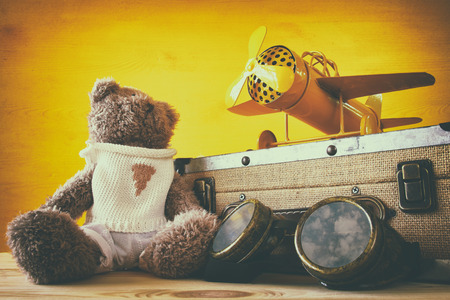 Photo of vintage toy plane and cute teddy bear on wooden tableの写真素材